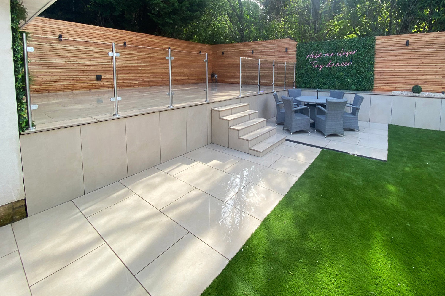 Forest Fern Artificial Green Wall Panels in a modern garden used as a backdrop for a pink neon sign and also for an outdoor screen
